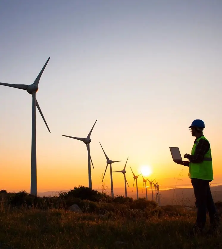 A person standing in front of wind turbines.