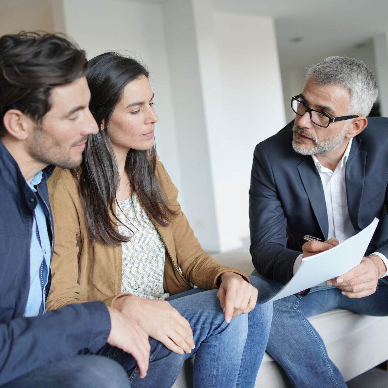 Couple with real-estate agent looking at contract in modern house